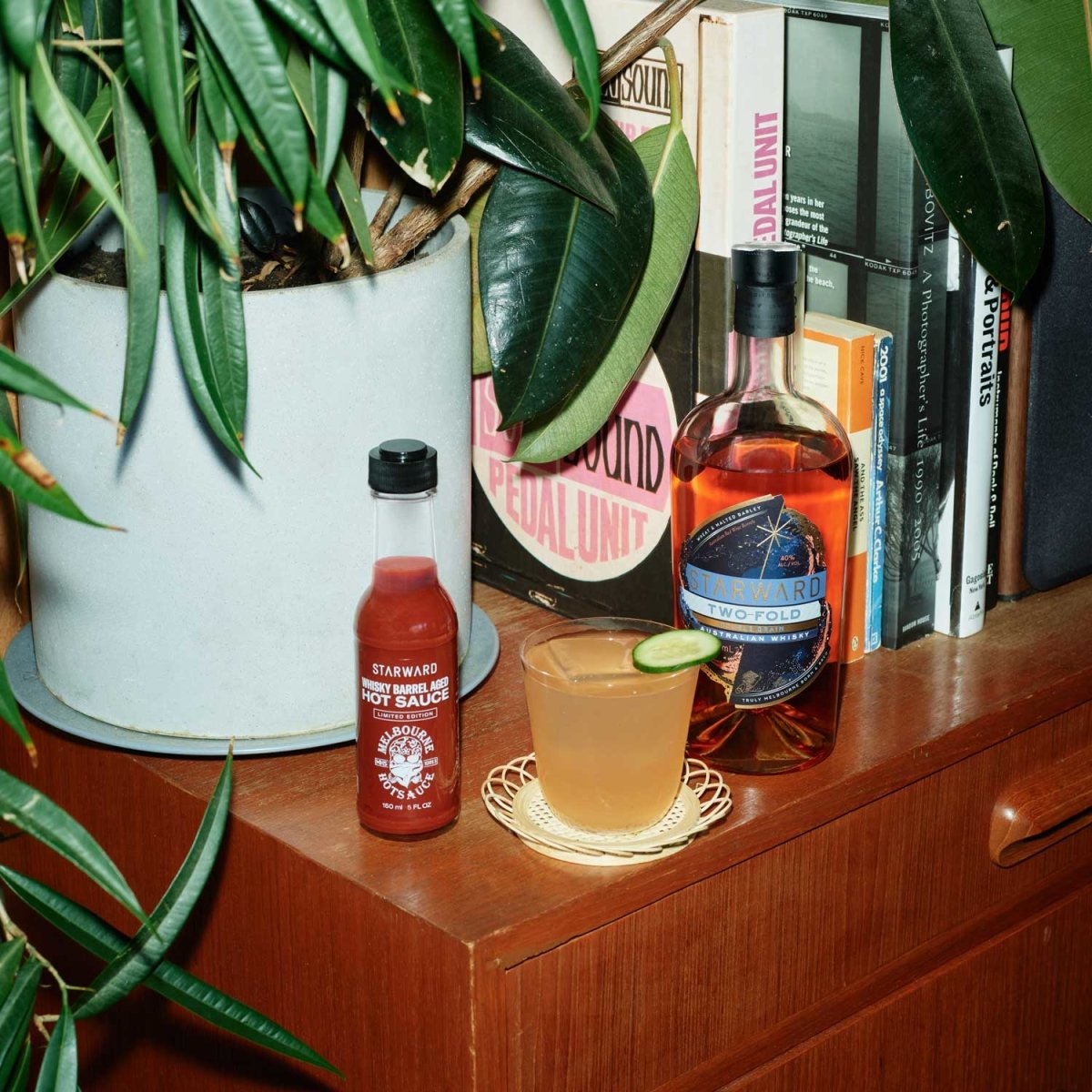 glass liquids red gold hot sauce bottle whisky amber plants green leaves wooden table