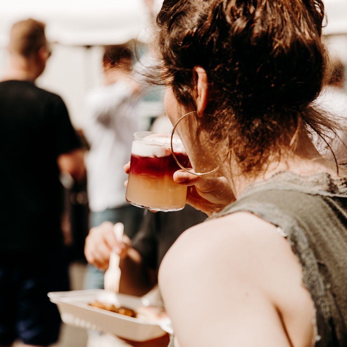 woman drinking cocktail glass layers liquids red yellow wine whisky foam white ice